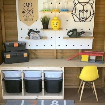 outdoor toy storage ideas using a play house with trays, baskets and a pegboard