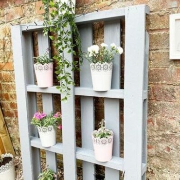 DIY garden pallet ideas using paint and leaning the pallet against the wall to use it as a shelf