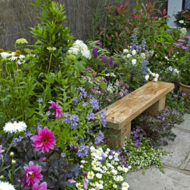 a rustic wooden bench tucked into an overflowing flowerbed