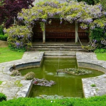 a wisteria-covered pergola overlooking a pond at Kingston Maurward Garden