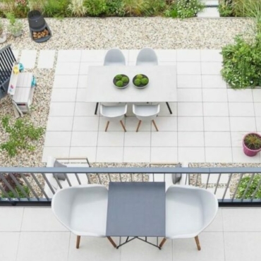a top-down view of a balcony overlooking a patio, both with cream paving stones