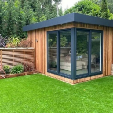 a modern, cube-shaped garden office in the corner of a garden
